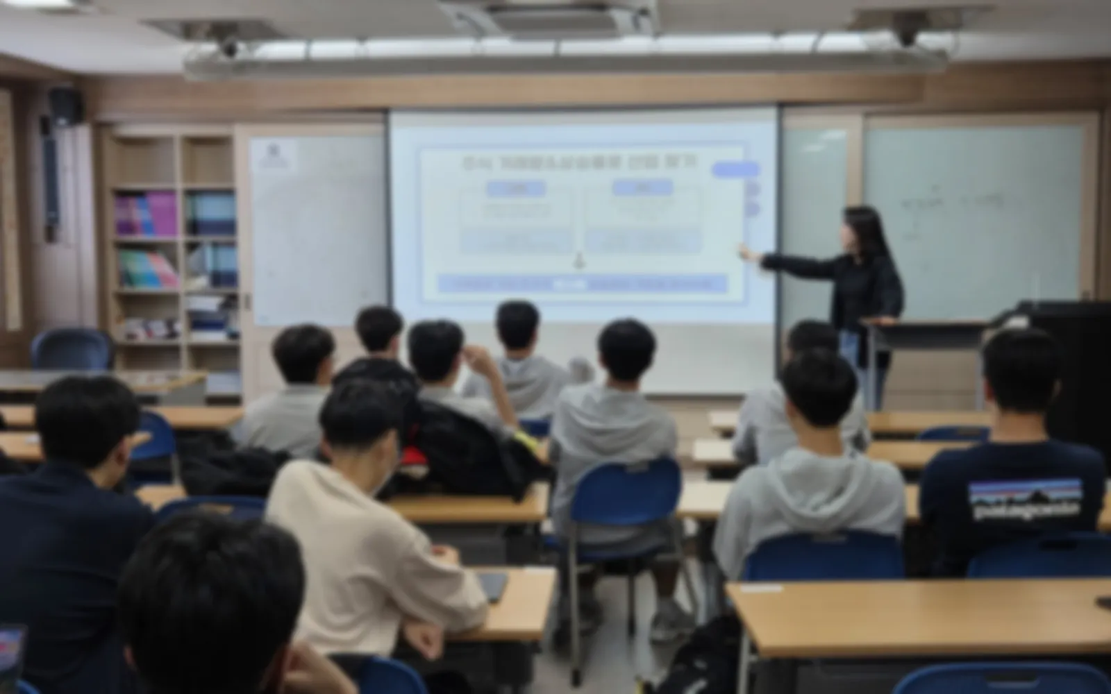 교실에서 대학생 멘토가 Plain 슬라이드로 경제교실 수업을 진행하는 모습